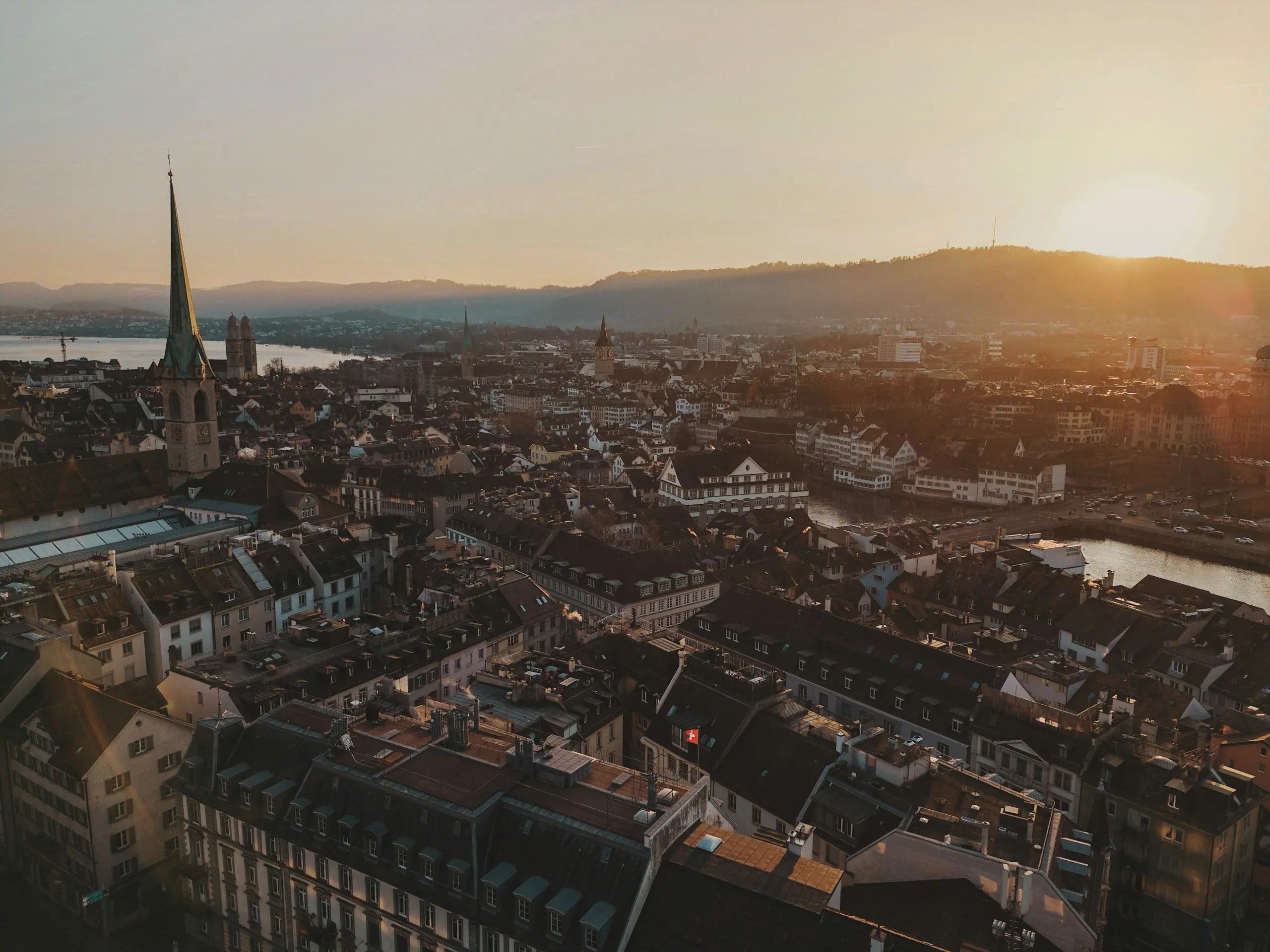 Zürich im goldenen Abendlicht: Altstadt mit Fraumünster und Grossmünster, Limmat und Zürichsee, dahinter die Hügel im Gegenlicht